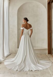 Alba - Stella's Bridal An a-line wedding dress in crepe, featuring a basque waitline and off-the-shoulder floral textured sleeves. Shown in Ivory and designed by Serene by Madi Lane Bridal. A modern bridal gown available at Stella’s Bridal in Westminster, Maryland. Serene by Madi Lane Bridal Style SR2000 Alba.