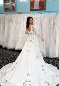 An a-line wedding dress in chiffon, featuring floral lace and spaghetti straps. Shown in Green floraly and Ivory and designed by Stella's Collection. A modern bridal gown available at Stella’s Bridal in Westminster, Maryland.