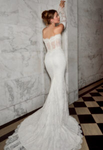 Cosette - Stella's Bridal A fitted wedding dress in lace, featuring a scalloped lace train and optional sleeves. Shown in Ivory and designed by Casablanca Bridal. A modern bridal gown available at Stella’s Bridal in Westminster, Maryland. Casablanca Bridal Style 2580 Cosette, inspired by Hailey Bieber's Wedding Dress.