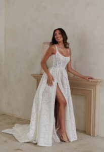 Bellamy - Stella's Bridal An a-line wedding dress in lace, featuring a high slit, square neckline, and optional sleeves. Shown in Ivory/Nude and designed by Serene by Madi Lane Bridal. A modern bridal gown available at Stella’s Bridal in Westminster, Maryland. Serene by Madi Lane Bridal Style SR2433 Bellamy.
