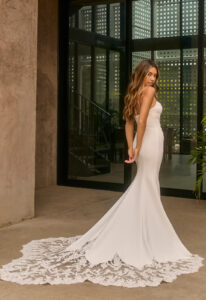 Agate - Stella's Bridal Beloved by Casablanca Agate wedding dress featuring a fitted silhouette with scoop neckline, crepe skirt, and lace train details. Available at Stella’s Bridal in Westminster, Maryland.