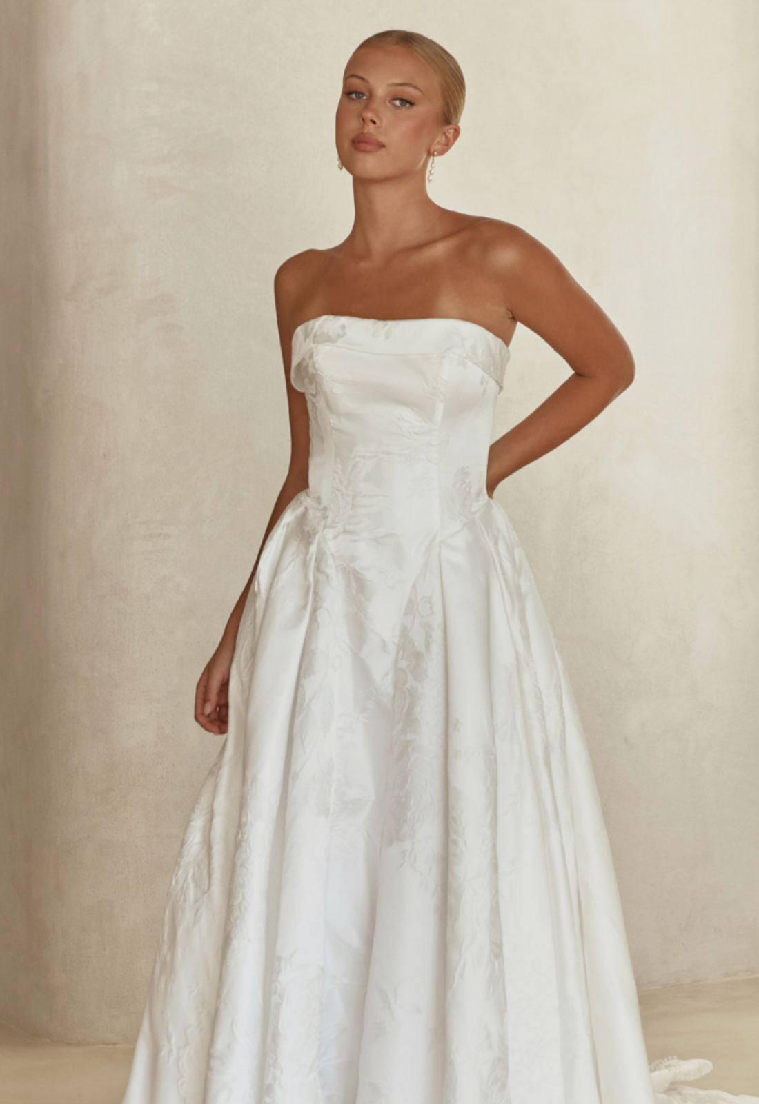 Serene by Madi Lane Clea wedding dress featuring an a-line silhouette with straight neckline, brocade skirt, and waterfall basque details. Available at Stella’s Bridal in Westminster, Maryland.