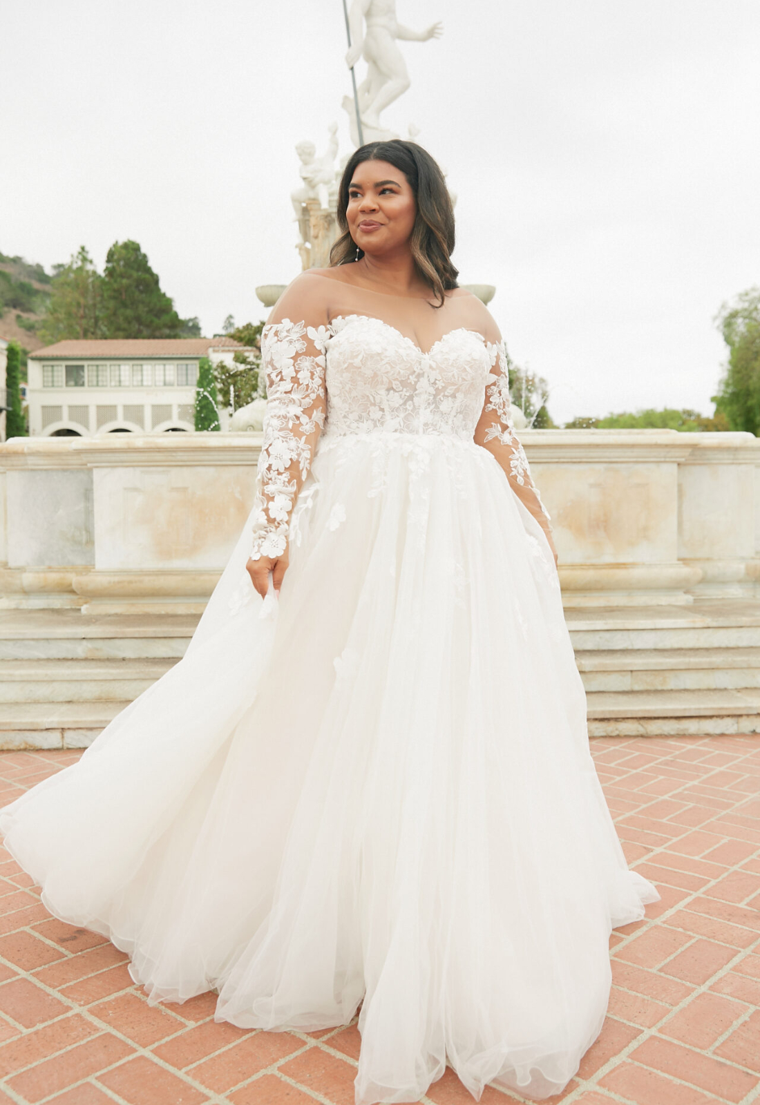 Esme - Stella's Bridal Stella York 8012 wedding dress featuring a ballgown silhouette with long sleeve illusion neckline, tulle skirt, and lace details. Available at Stella’s Bridal in Westminster, Maryland.