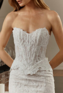 Janet - Stella's Bridal Evie Young Janet wedding dress featuring a fitted peplum silhouette with sweetheart neckline, lace skirt, and corseted details. Available at Stella’s Bridal in Westminster, Maryland.
