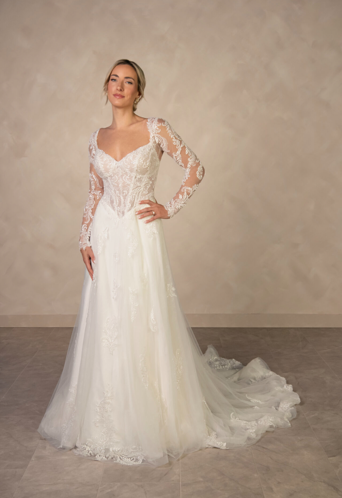 Lena - Stella's Bridal Essense of Australia D4577 wedding dress featuring an a-line silhouette with long sleeve v-neck neckline, tulle skirt, and sparkling lace details. Available at Stella’s Bridal in Westminster, Maryland.