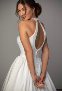 Stella York SY8273 wedding dress featuring an a-line silhouette with halter neckline, satin skirt, and pleated details. Available at Stella’s Bridal in Westminster, Maryland.