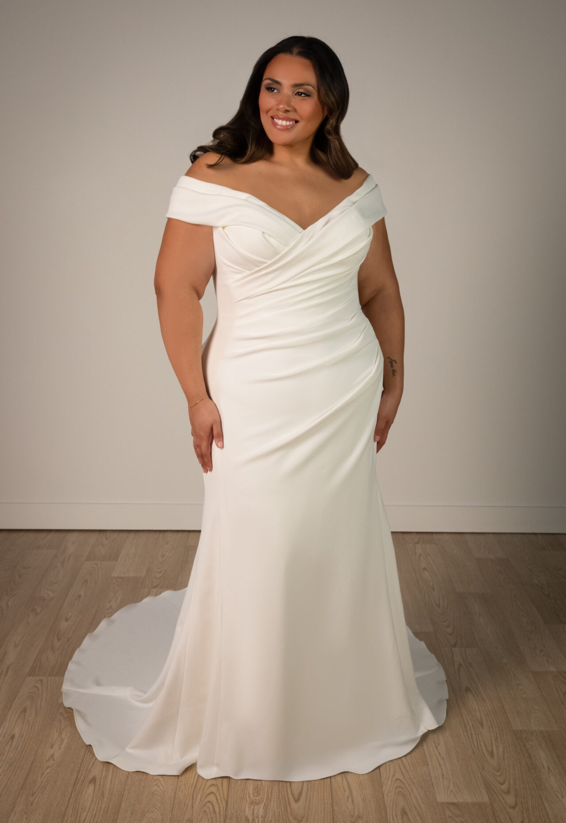 Nelly - Stella's Bridal Stella York SY8330 wedding dress featuring a fitted silhouette with off-the-shoulder neckline, crepe skirt, and ruched details. Available at Stella’s Bridal in Westminster, Maryland.