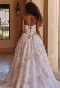 Orsina - Stella's Bridal Madi Lane Orsina wedding dress featuring a ballgown silhouette with ruffled neckline, floral organza skirt, and corseted details. Available at Stella’s Bridal in Westminster, Maryland.