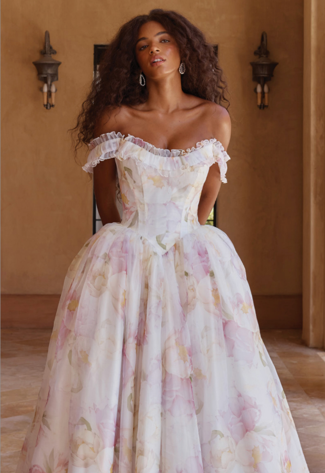 Orsina - Stella's Bridal Madi Lane Orsina wedding dress featuring a ballgown silhouette with ruffled neckline, floral organza skirt, and corseted details. Available at Stella’s Bridal in Westminster, Maryland.