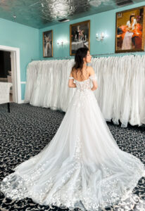 Love it at Stella's Exclusive Shreya wedding dress featuring an a-line silhouette with plunging sweetheart neckline, detachable sleeves, and leafy lace details. Available at Stella’s Bridal in Westminster, Maryland.