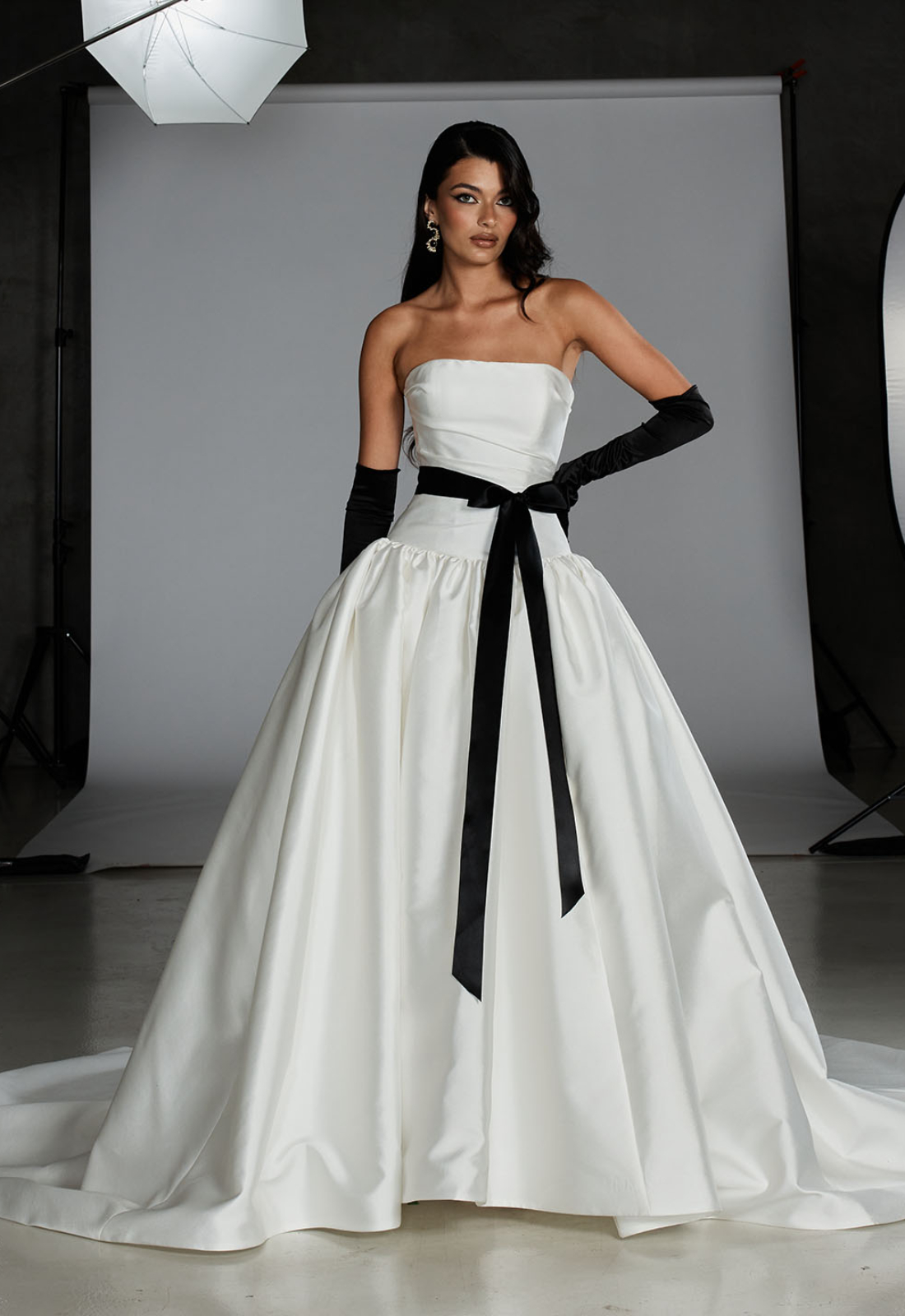 Evie Young O'Hara wedding dress featuring a fitted drop waist silhouette with straight neckline, black accent, and ruched details. Available at Stella’s Bridal in Westminster, Maryland.